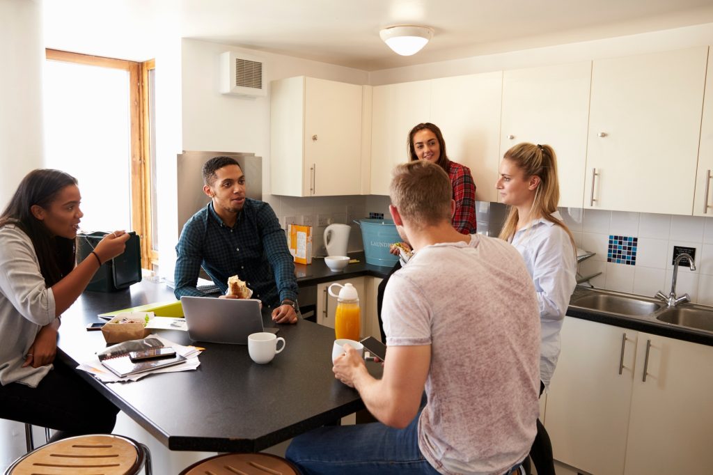 Students Relaxing In Kitchen Of Shared Accommodation